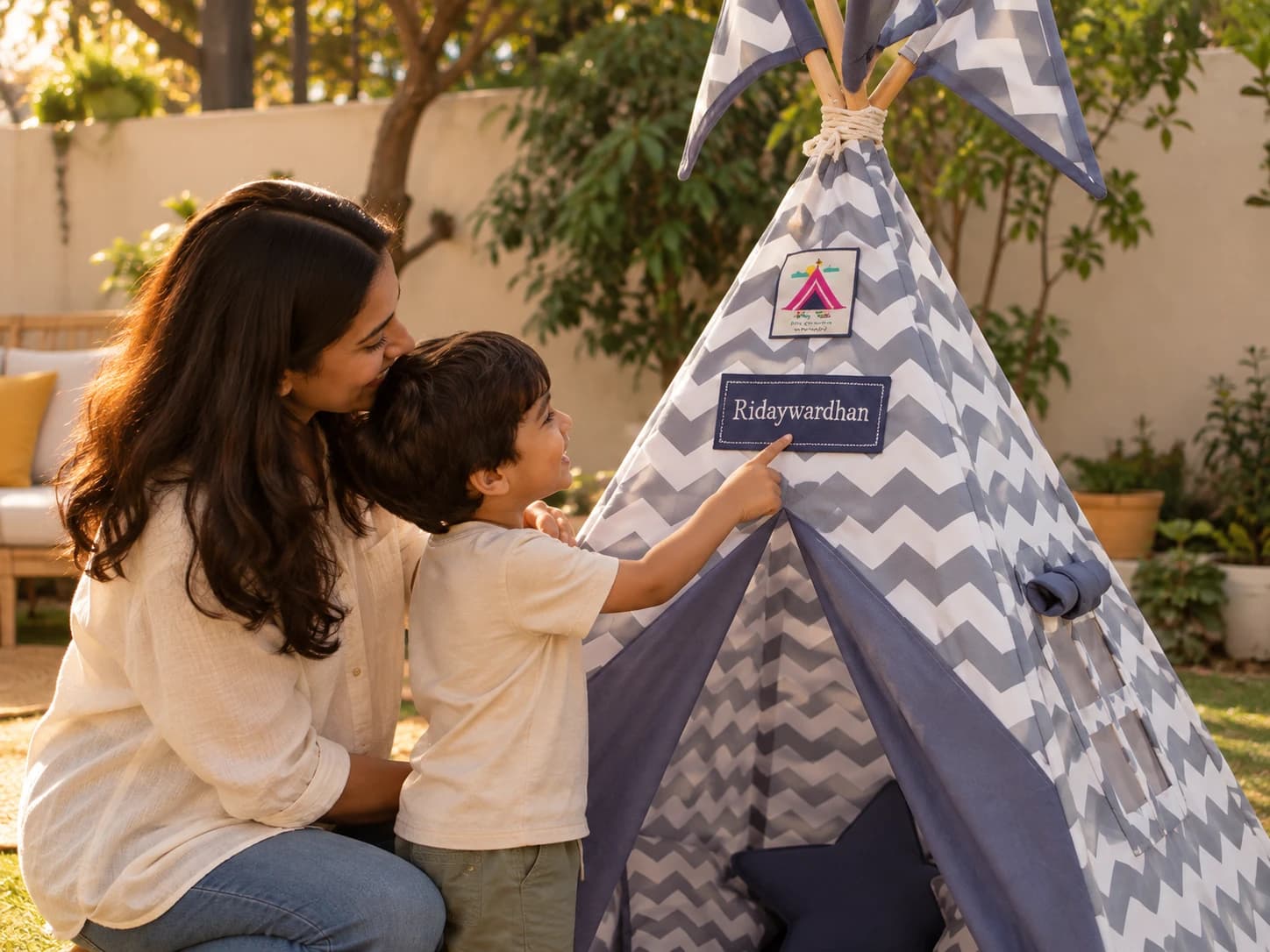 A mother and her son look at the name patch on the front of a grey chevron teepee.
